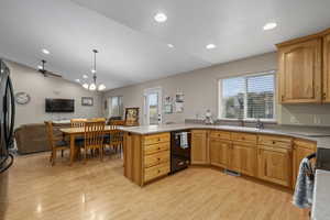 Kitchen featuring lofted ceiling, sink, hanging light fixtures, light hardwood / wood-style floors, and kitchen peninsula