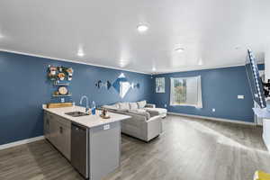 Kitchen with hardwood / wood-style flooring, stainless steel dishwasher, and sink