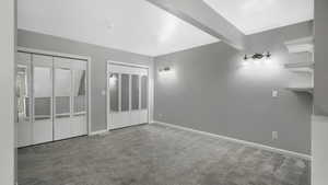 Unfurnished bedroom featuring carpet floors, beamed ceiling, and two closets