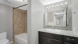 Full bathroom with tiled shower / bath, vanity, and toilet