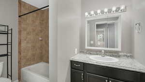 Full bathroom with vanity, tiled shower / bath combo, and toilet