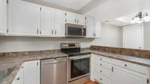 Kitchen featuring white cabinets, sink, and appliances with stainless steel finishes