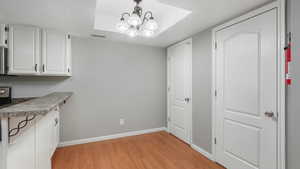 Unfurnished dining area featuring a textured ceiling, light hardwood / wood-style flooring, and a notable chandelier