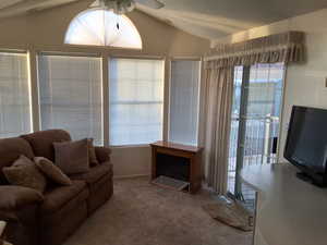 Carpeted living room featuring ceiling fan and lofted ceiling