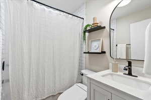 Bathroom featuring curtained shower, vanity, and toilet