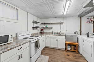 Kitchen featuring white appliances, washer and clothes dryer, sink, white cabinets, and dark hardwood / wood-style floors