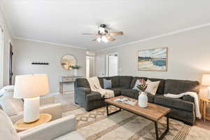 Living room featuring ceiling fan and ornamental molding