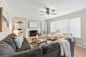 Living room featuring a fireplace, a wealth of natural light, and ornamental molding