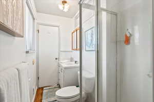 Bathroom featuring walk in shower, toilet, vanity, and hardwood / wood-style flooring