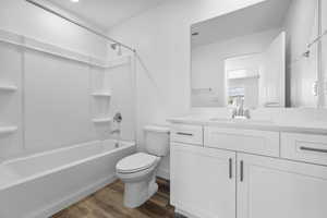 Full bathroom with hardwood / wood-style floors, vanity, toilet, and washtub / shower combination