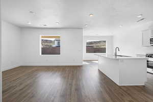 Kitchen featuring white appliances, a kitchen island with sink, white cabinets, sink, and dark hardwood / wood-style floors