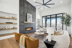 Living room featuring a tile fireplace, ceiling fan, light hardwood / wood-style flooring, and built in features