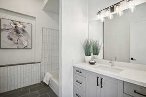 Bathroom with tile patterned floors, vanity, and tiled shower / bath combo