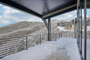 Snow covered patio featuring a mountain view and a balcony