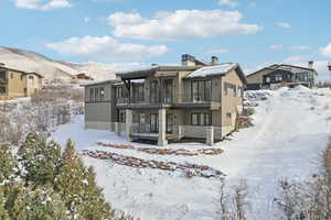 Snow covered rear of property with a mountain view and a balcony