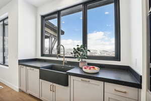 Kitchen featuring hardwood / wood-style floors, white cabinetry, and sink