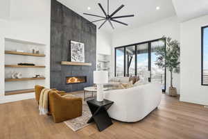 Living room featuring a tile fireplace, ceiling fan, light hardwood / wood-style flooring, and built in shelves