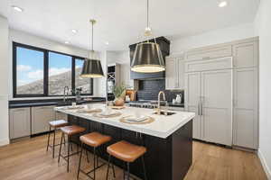 Kitchen featuring a center island with sink, decorative light fixtures, gray cabinets, and light hardwood / wood-style floors