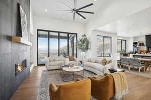 Living room with a mountain view, ceiling fan, high vaulted ceiling, a fireplace, and light hardwood / wood-style floors