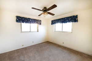 Carpeted spare room featuring ceiling fan