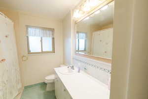 Bathroom with tile patterned flooring, vanity, toilet, and crown molding