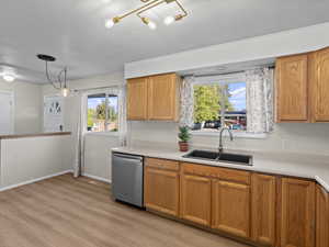 Kitchen featuring stainless steel dishwasher, plenty of natural light, light wood-type flooring, and sink