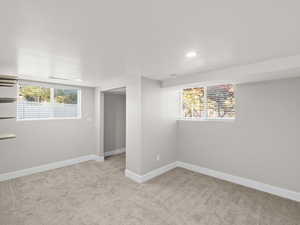 Basement with light carpet and a healthy amount of sunlight