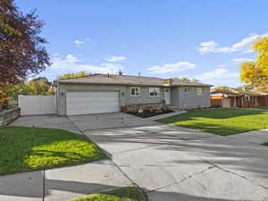 Ranch-style home featuring a garage and a front lawn