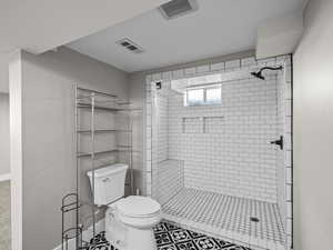 Bathroom with tile patterned floors, toilet, and tiled shower