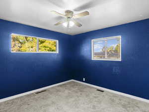 Spare room featuring carpet and ceiling fan