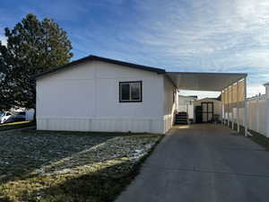 View of side of home with a carport and a storage unit