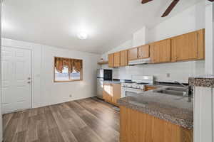 Kitchen featuring sink, hardwood / wood-style flooring, ceiling fan, stainless steel fridge, and white gas stove