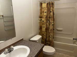 Full bathroom with shower / bath combo, vanity, toilet, and tile patterned floors