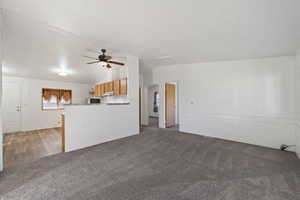 Unfurnished living room featuring light carpet, ceiling fan, and lofted ceiling