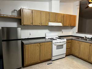 Kitchen featuring stainless steel fridge, gas range gas stove, ceiling fan, sink, and lofted ceiling