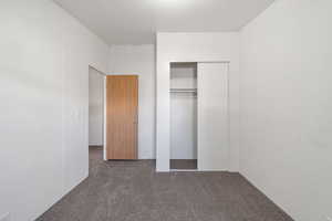 Unfurnished bedroom featuring dark colored carpet and a closet