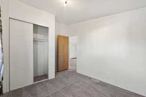 Unfurnished bedroom featuring light carpet and a closet