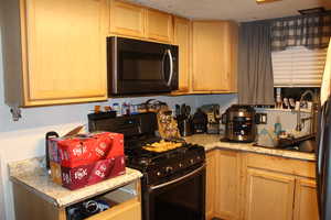 Duplex # A Kitchen featuring black range with gas stovetop, a textured ceiling, and light brown cabinetry