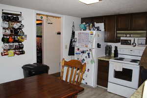 Duplex # B Kitchen featuring a textured ceiling, white appliances, and dark brown cabinetry