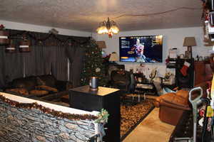 Duplex # A Living room featuring carpet flooring, a textured ceiling, and a notable chandelier