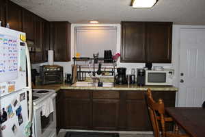 Duplex # B Kitchen with a textured ceiling, white appliances, dark brown cabinets, and sink