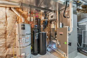 Utility room featuring strapped water heater