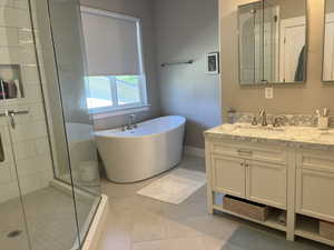 Bathroom featuring tile patterned floors, vanity, and shower with separate bathtub