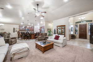 Living room featuring a chandelier, lofted ceiling, light carpet, a ceiling fan, and recessed lighting