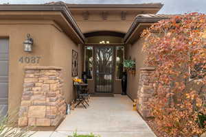 Entrance to property with stucco siding, stone siding, and a patio area