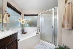 Bathroom featuring a bath, vanity, and a stall shower