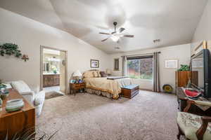 Carpeted bedroom with lofted ceiling, ensuite bathroom, and a ceiling fan