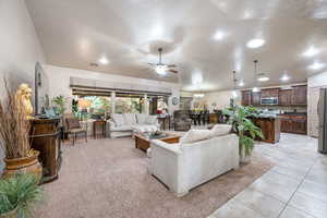 Living area with ceiling fan, recessed lighting, light tile patterned floors, and a chandelier