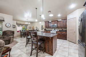 Kitchen featuring dark brown cabinets, a breakfast bar area, dark stone counters, decorative backsplash, and appliances with stainless steel finishes
