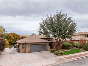 View of front of house with stone siding, stucco siding, driveway, a tiled roof, and a garage